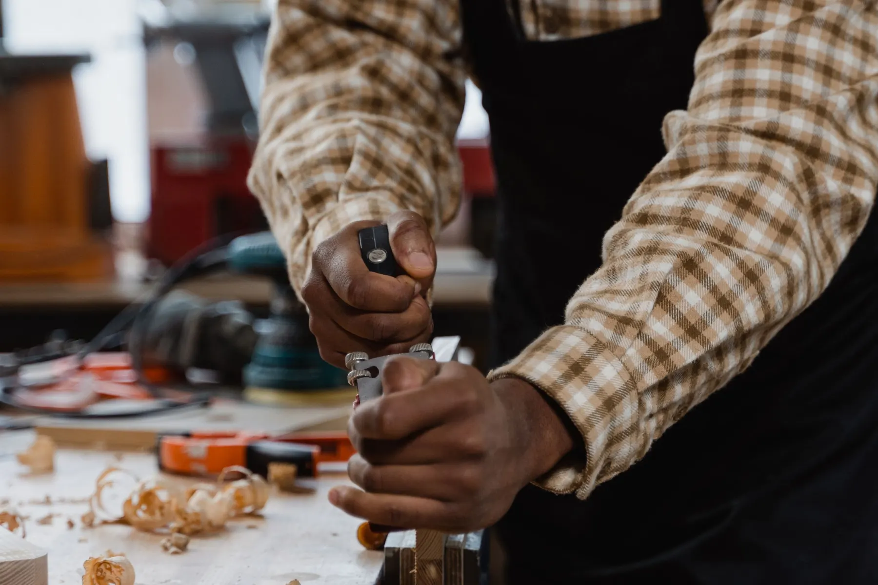Die Hände eines Handwerkers schieben einen Hobel über ein Brett